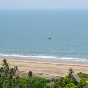 Wide shot of the Vagator Beach as seen from top of the Chapora fort in front of the blue Arabian sea at Goa in India. Rocky landscape with palm trees on a tropical island. Vacation background at sea.
